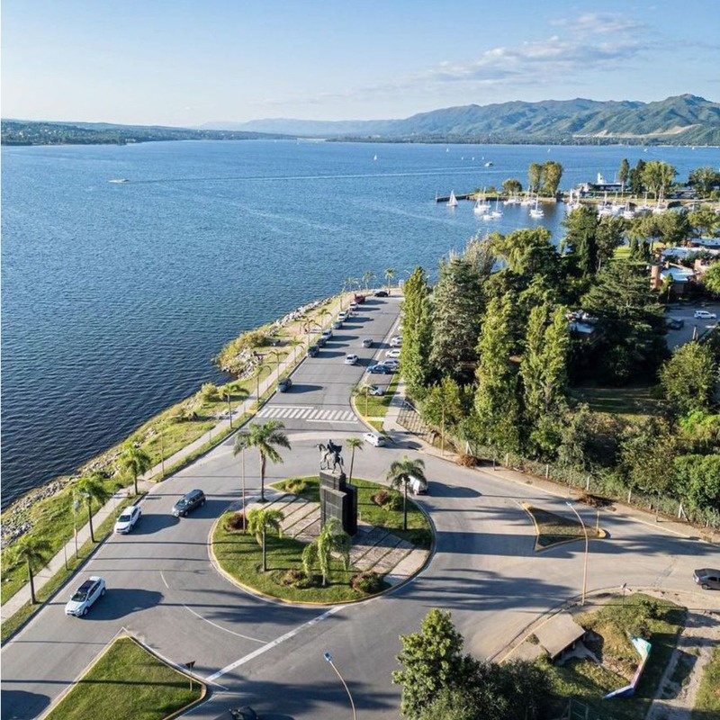 Vista aérea de la costanera de Villa Carlos Paz y el Lago San Roque con las sierras de fondo